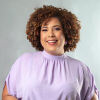 Raíssa França é uma mulher negra não retinta, de cabelos crespos, castanhos, na altura do ombro
