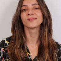 Victoria tem cabelo castanho claro longo, usa um piercing no nariz e tem a cabeça levemente levantada