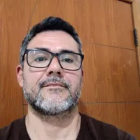 Homem de pele clara, com barba curta e grisalha, cabelo curto e óculos.
