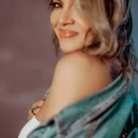 Tayná é uma mulher de pele clara, cabelos longos castanhos com mechas loiras e está de perfil na foto