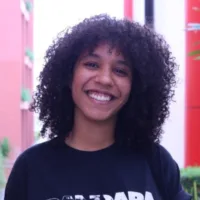 Mulher negra de pele clara, e cabelos crespos de tamanho médio.