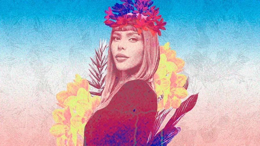 Ilustração em tons de rosa, azul e amarelo de Patty Michelletti, que tem cabelos lisos e usa franja. Ela está com uma coroa de flores coloridas, cercada por flores e folhas, em fundo degradê suave, representando a força e a delicadeza das mulheres trans.