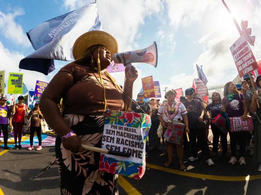 Mulher negra protesta com um megafone na Marcha Global pelo Clima, em Belém (PA). Enquanto segura um cartaz.