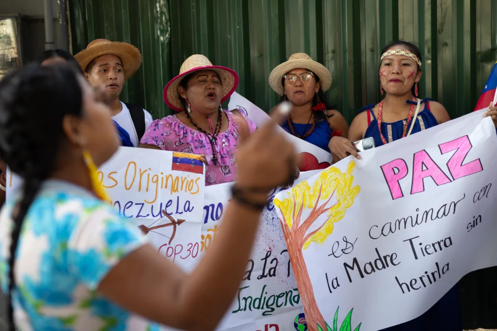 Quatro mulheres latinas seguram cartazes em protesto durante a Marcha Global pela Justiça Climática em Belém (PA).