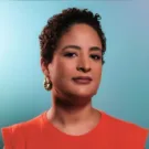 mulher negra clara de cabelos curtos, batom escuro e blusa laranja