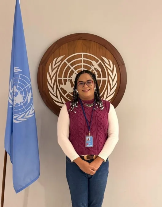Luana Barbosa, diretora da Pajubá Tech, posa diante do símbolo da ONU