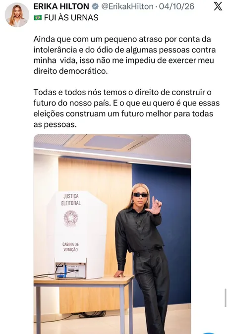 Erika Hilton posa ao lado de uma urna eletrônica em uma seção eleitoral